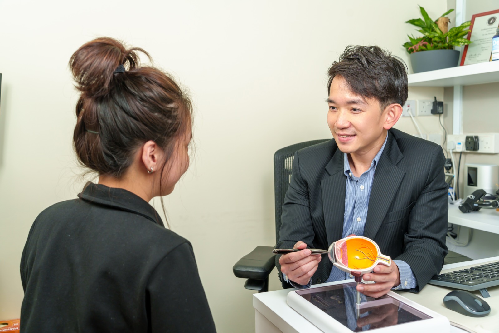 Dr. Wong consulting with a patient using an eye anatomy model